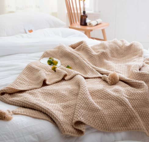 Gebreide plaid met pompons over de bank