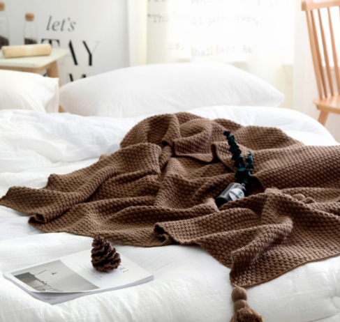 Gebreide plaid met pompons over de bank