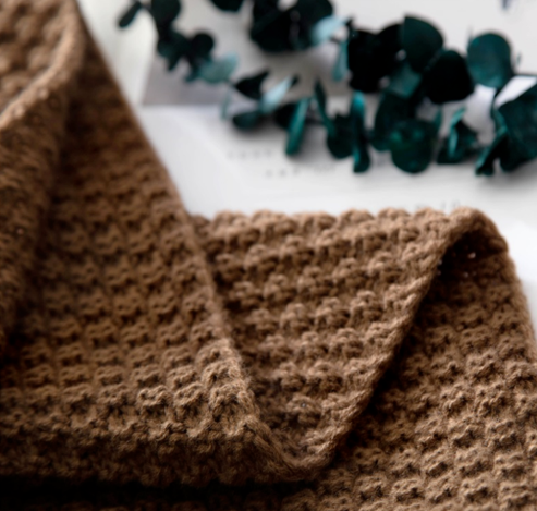 Gebreide plaid met pompons over de bank