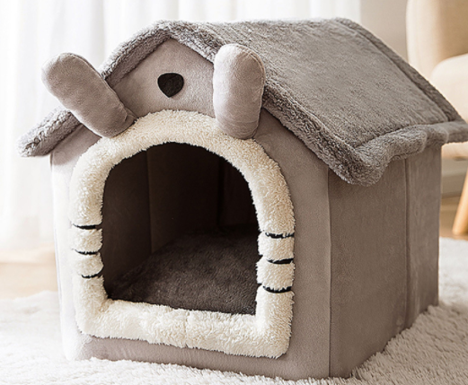 Kat kijkt uit een grijs pluche kattenhuisje