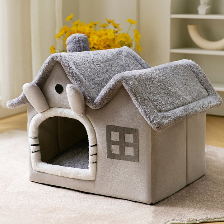 Kat kijkt uit een grijs pluche kattenhuisje