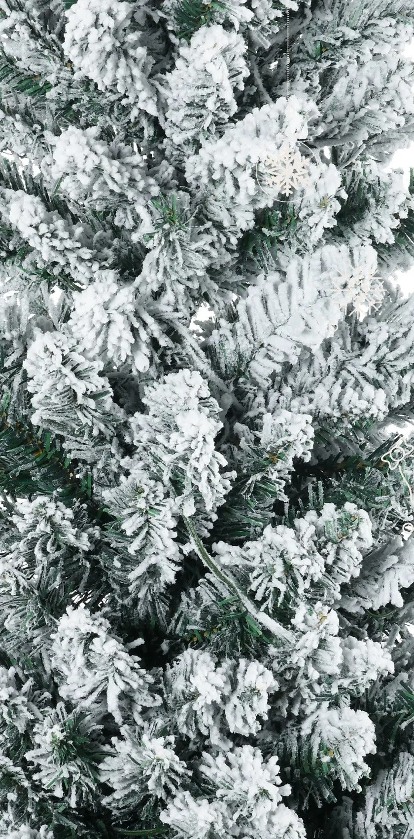 Smalle besneeuwde kerstboom met warmwitte lichtjes
