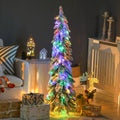 Kleine smalle besneeuwde kerstboom met lichtjes