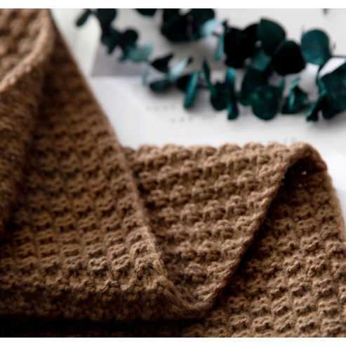 Wafelgebreide plaid met pompons voor op de bank
