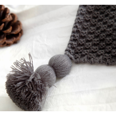 Wafelgebreide plaid met pompons voor op de bank