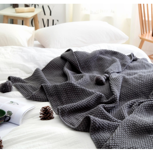 Wafelgebreide plaid met pompons voor op de bank