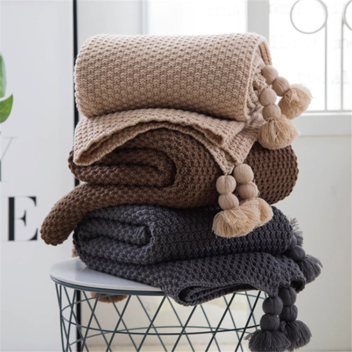 Wafelgebreide plaid met pompons voor op de bank