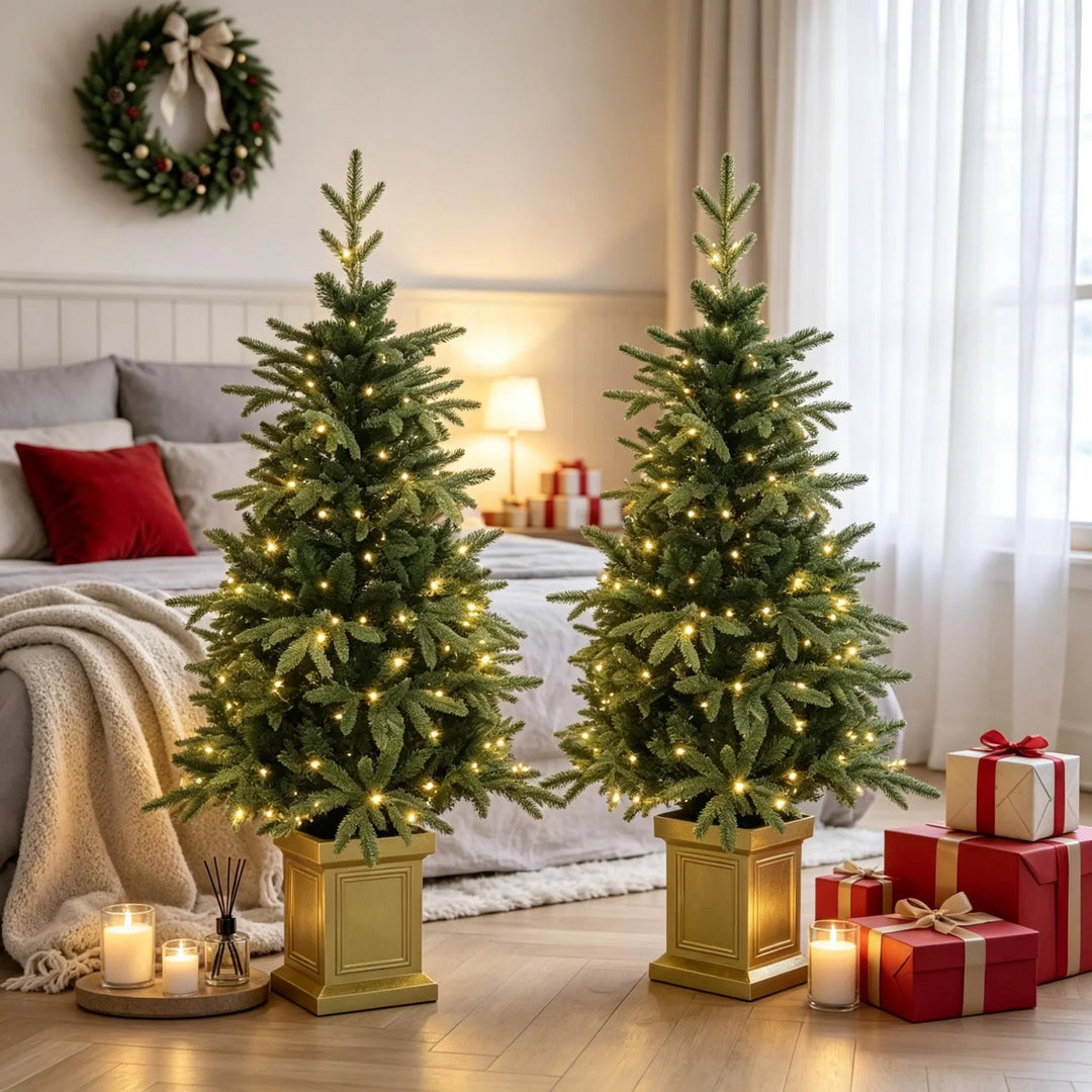 Twee kerstboompjes in gouden potten met lichtjes